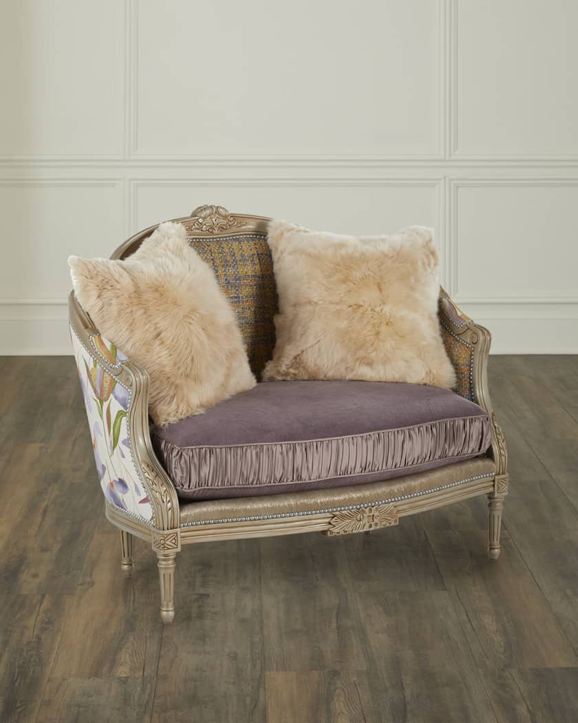 Decorative loveseat with floral patterned backrest and fur cushions on a wooden floor.