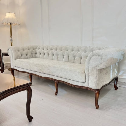 Vintage-style sofa with wooden legs in a room with a lamp and white walls.