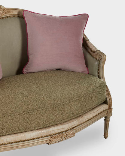 Vintage-style sofa with ornate detailing and a pink cushion on a white background