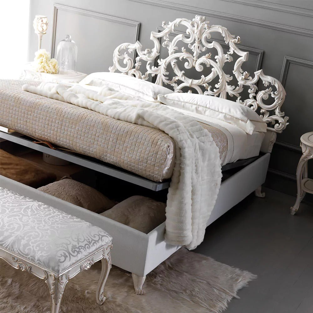 Decorative white bed with intricate headboard in a room setting.
