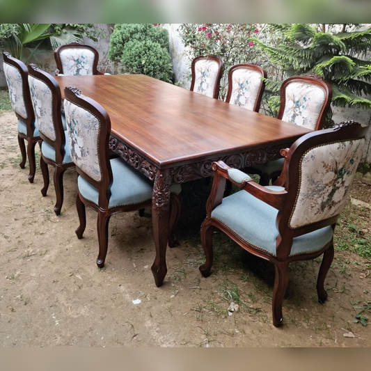 Wooden dining table with chairs outdoors on a dirt surface