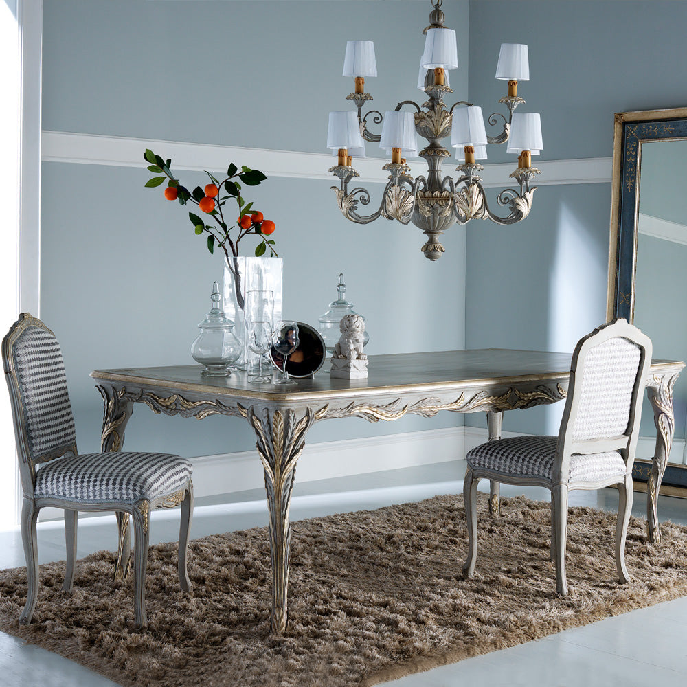 Dining room with ornate table and chairs, chandelier, and decorative items.