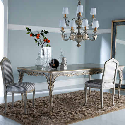 Dining room with ornate table and chairs, chandelier, and decorative items.
