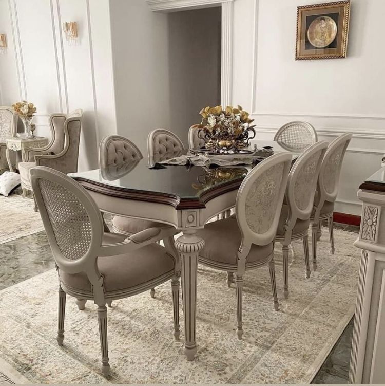 An elegant 8-seater dining set with a dark mahogany table and beige upholstered chairs with cane details, situated in a luxurious dining room setting.