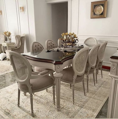 An elegant 8-seater dining set with a dark mahogany table and beige upholstered chairs with cane details, situated in a luxurious dining room setting.