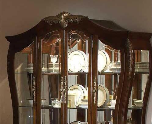 Wooden china cabinet with glass doors displaying plates and glasses.