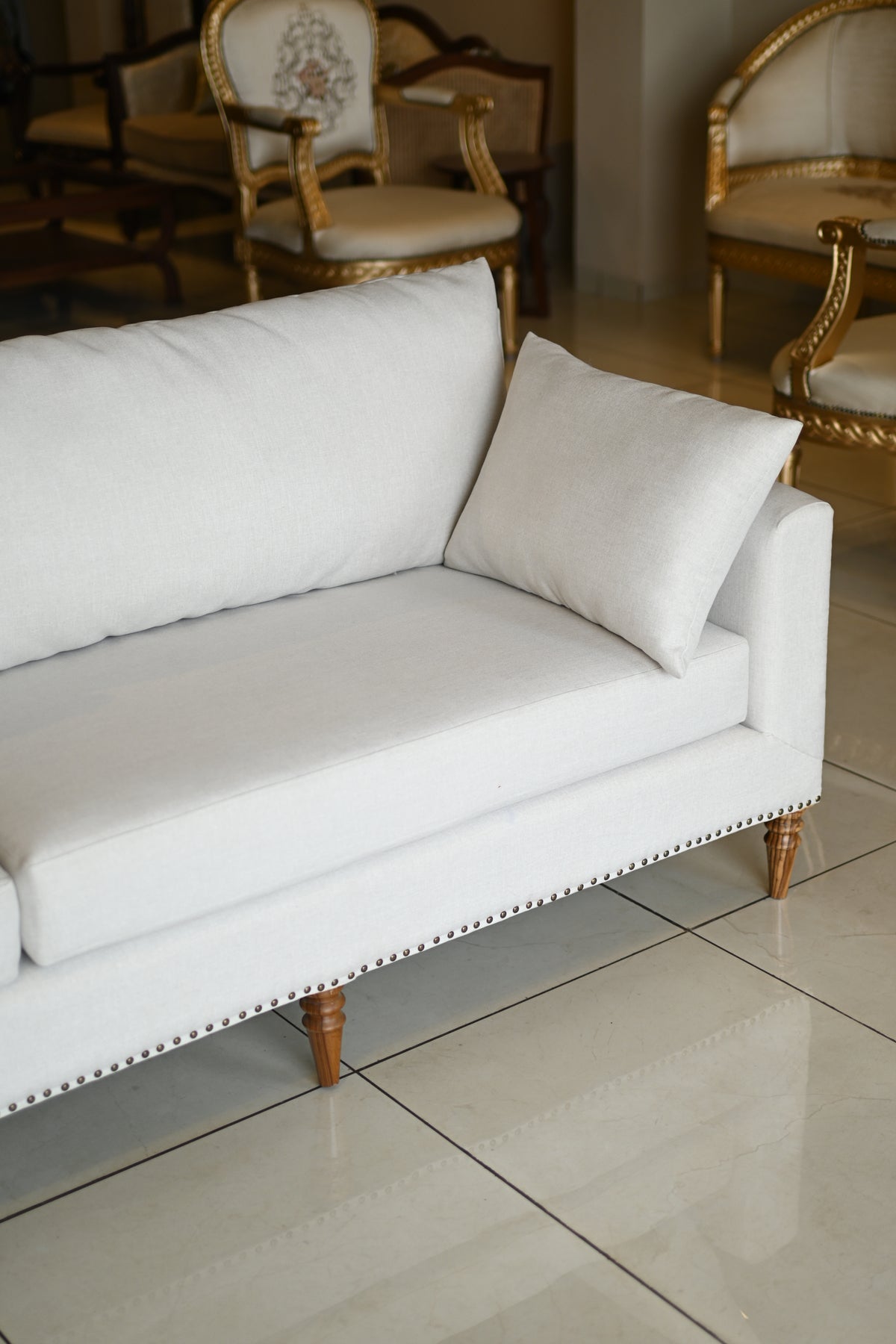 White upholstered chair with gold legs in a room setting