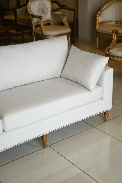 White upholstered chair with gold legs in a room setting