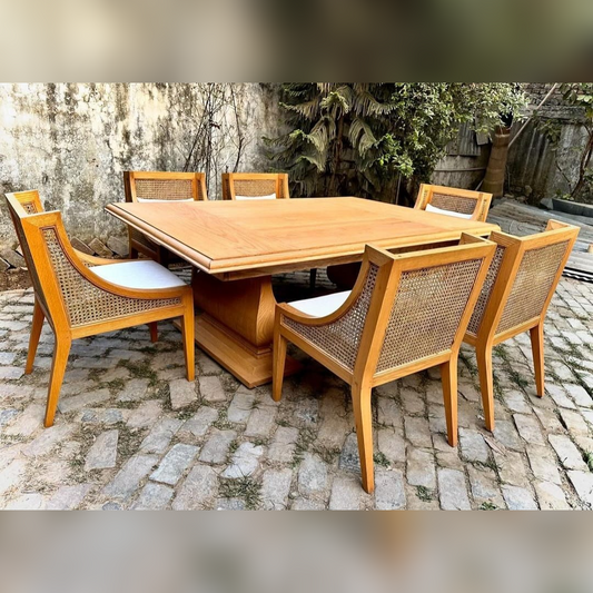 Wooden dining table with six matching chairs on a stone patio.