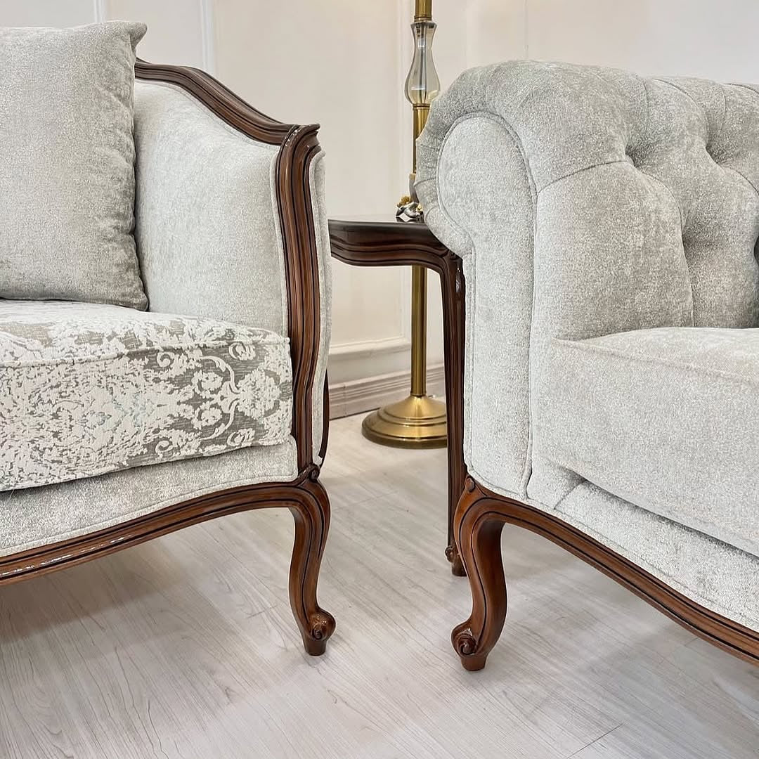 Two gray upholstered chairs with wooden frames in a room setting.