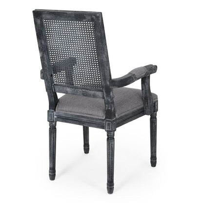 A black distressed French finish dining chair with cane back and linen fabric upholstery, viewed from a rear angle.