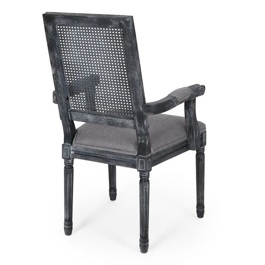 A black distressed French finish dining chair with cane back and linen fabric upholstery, viewed from a rear angle.
