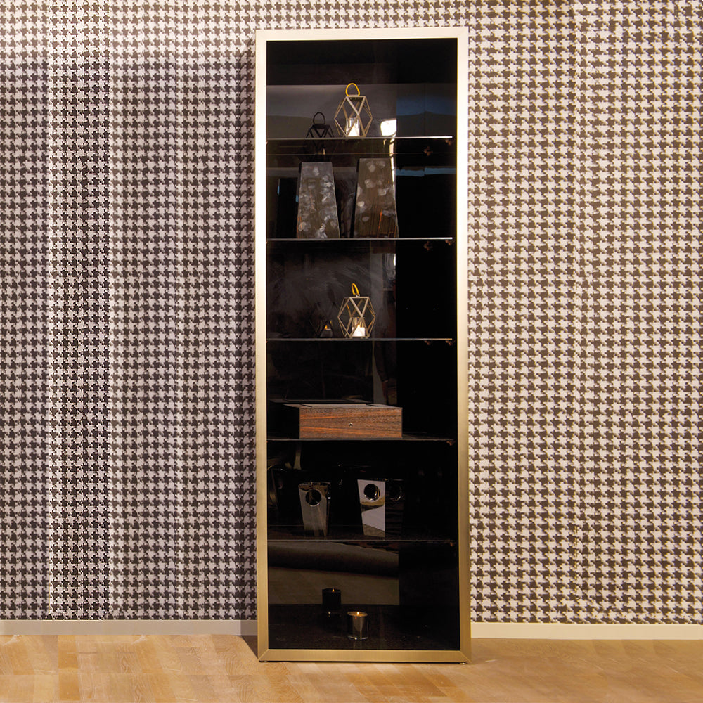 A tall mahogany veneer display cabinet with antique gold accents, glass shelves, and items displayed inside, standing against a houndstooth wallpaper background.