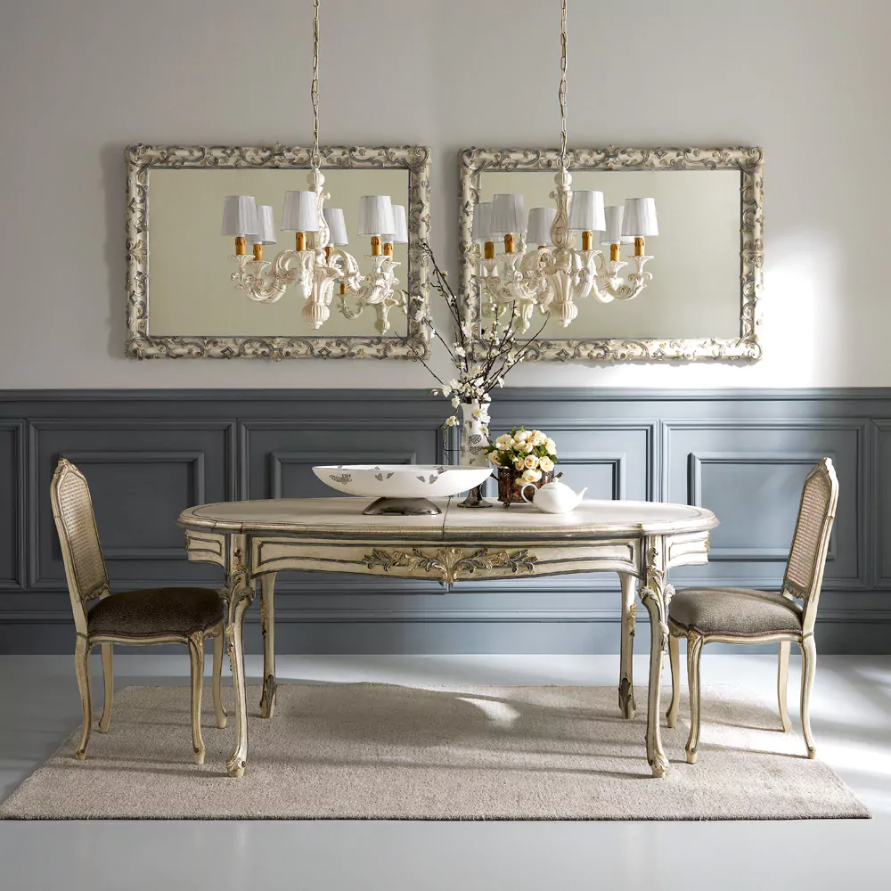 Dining room with ornate table and chairs, framed mirrors, and chandelier.