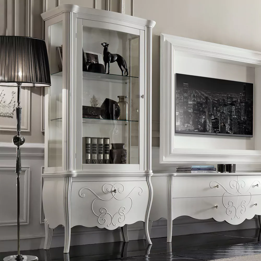 A white display cabinet with glass shelves and patterned drawer, placed in a room with a light interior.